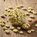 Bitter Apple (Indrayan/Hanzal/Citrullus Colocynthis) dried pale yellow-green fruits on wooden surface with glass bowl and wooden spoon