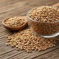 Carrot Seeds (Tukhm-e-Gajar/Daucus Carota) small pale tan-brown oval seeds on wooden surface with glass bowl and wooden spoon