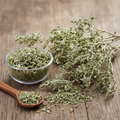 Dried Wormwood (Afsanteen) herb on wooden surface with glass bowl and wooden spoon