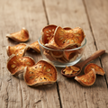 Bael Fruit (Bel/Aegle Marmelos) dried golden slices on wooden surface with glass bowl and wooden spoon