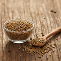 Celery Seeds on wooden surface with glass bowl and wooden spoon