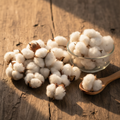 Indian Cotton Seeds (Tukhm-e-Karpas) on wooden surface with glass bowl and wooden spoon