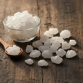 Camphor (Kafoor/Cinnamomum Camphora) white translucent crystals and chunks on wooden surface with glass bowl and wooden spoon