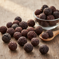 Aleppo Oak galls (Manjakani/Mazoo) on wooden surface with glass bowl and wooden spoon