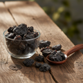 Black Dammar resin (Dammar Siyah/Canarium Strictum) dark black-brown chunks on wooden surface with glass bowl and wooden spoon