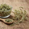 Common Fumitory (Shahtra/Fumaria Officinalis) dried pale green-grey stems and delicate leaves on wooden surface with glass bowl and wooden spoon