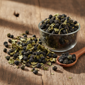 Black Nightshade (Makoh/Solanum Nigrum) dried dark black-green berries and leaves on wooden surface with glass bowl and wooden spoon