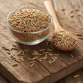 Chicory Seeds (Tukhm-e-Kasni/Cichorium Intybus) tiny slender pale brown seeds on wooden surface with glass bowl and wooden spoon