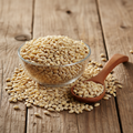 Barley grains (Jau/Sha'eer) on wooden surface with glass bowl and wooden spoon