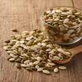 Char Magaz (Four Kernels) mix of watermelon, muskmelon, pumpkin and cucumber seeds on wooden surface with glass bowl and wooden spoon